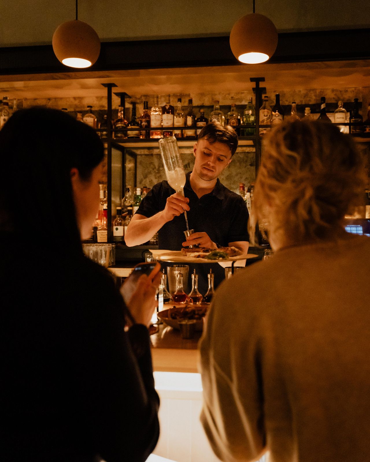 A bartender finishing a cocktail garnish at the Odd Sister bar