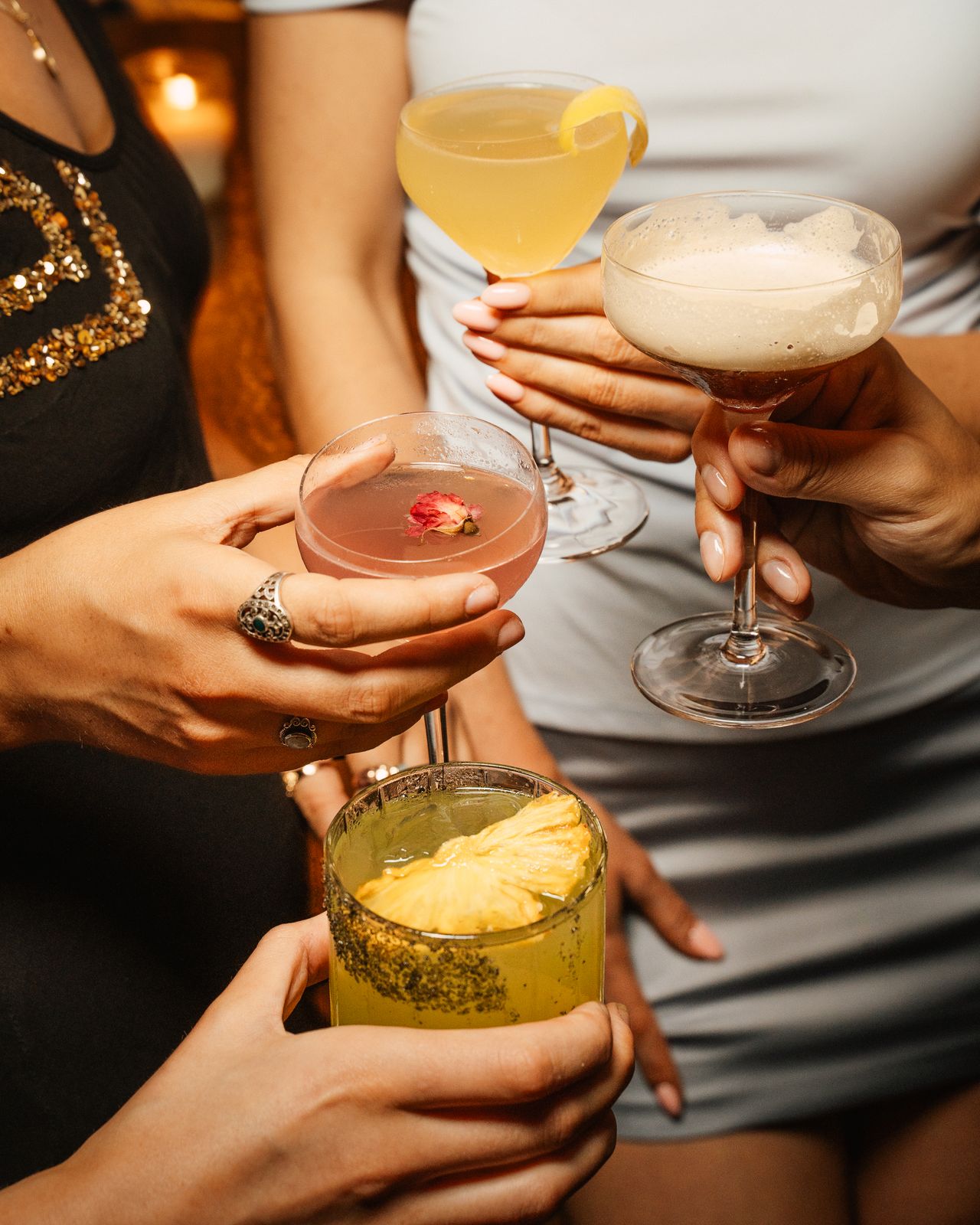 Three hand-garnished cocktails held up mid-toast at Odd Sister