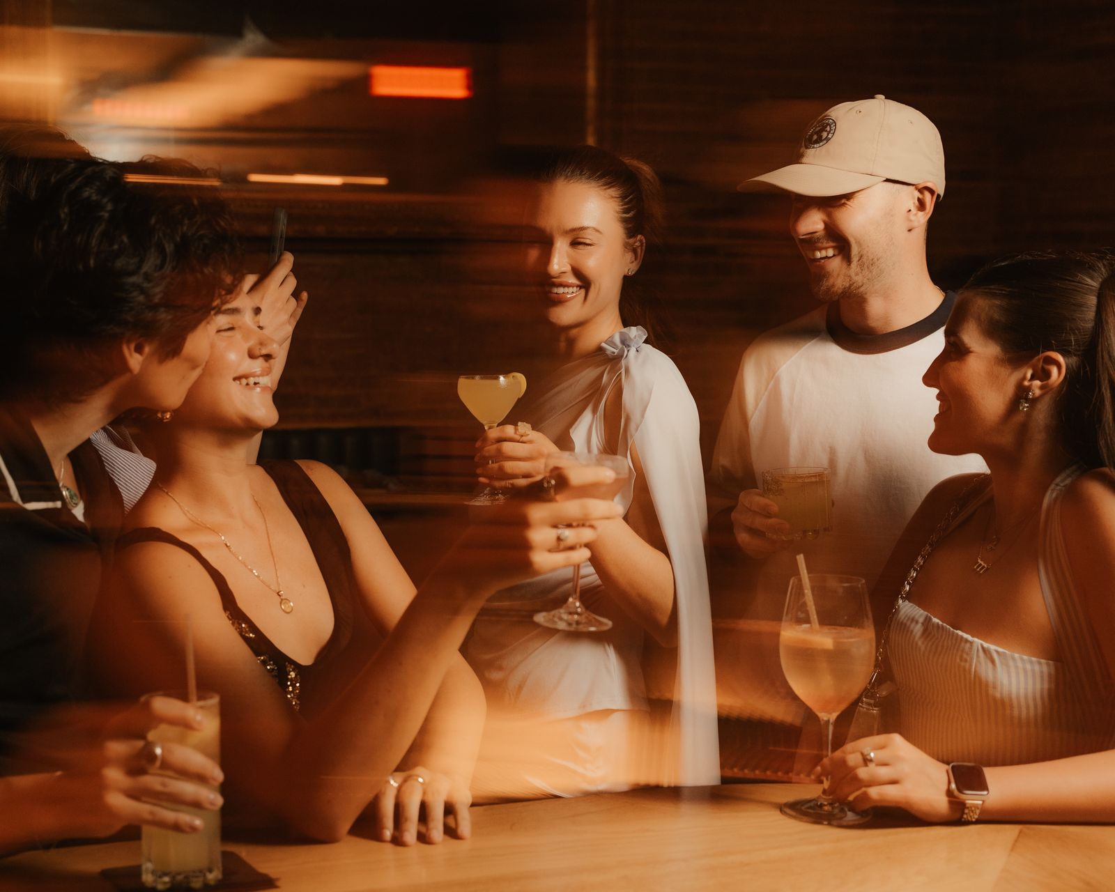 Friends toasting at the Odd Sister bar in warm evening light