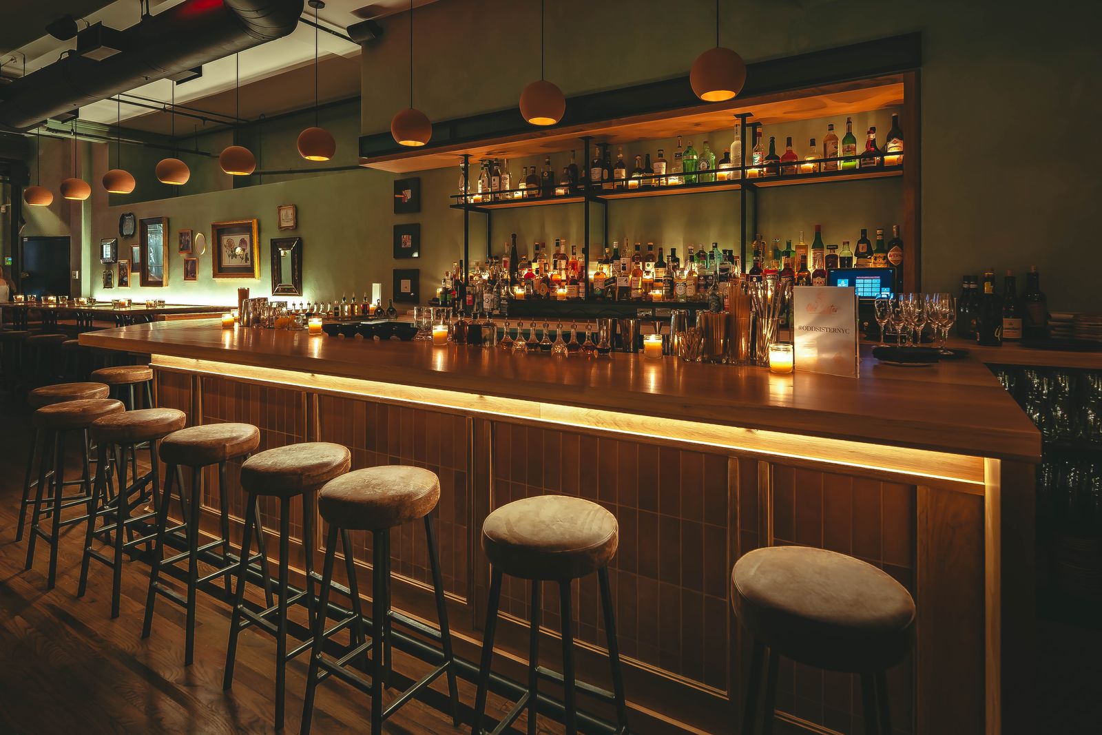 Odd Sister's bar, lit by globe pendants, lined with spirits