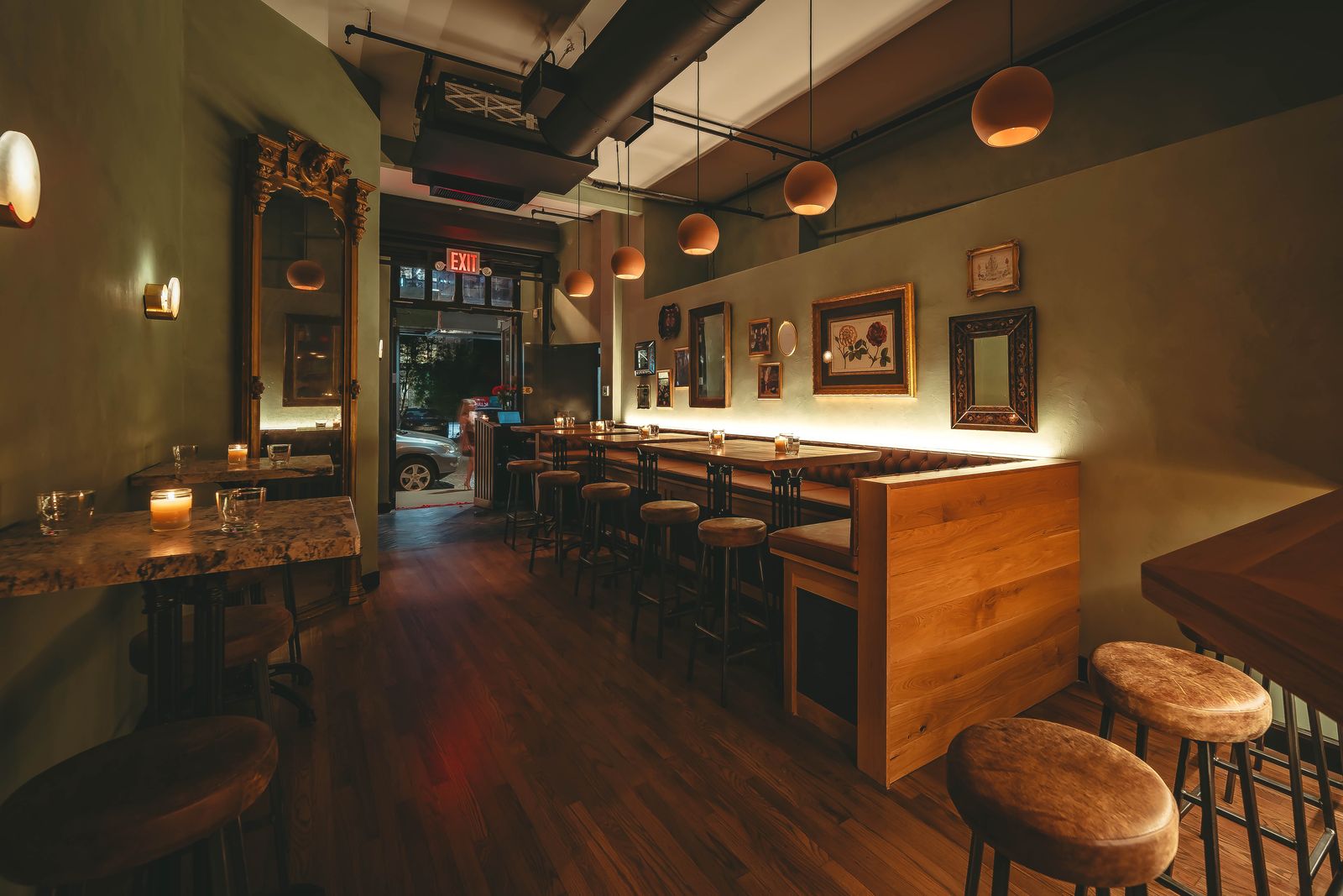 Odd Sister's skylit backroom seating at dinner, framed mirrors along a sage-green wall